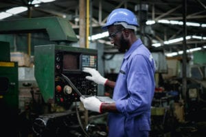 Manufacturing worker in blue jumpsuit with laptop